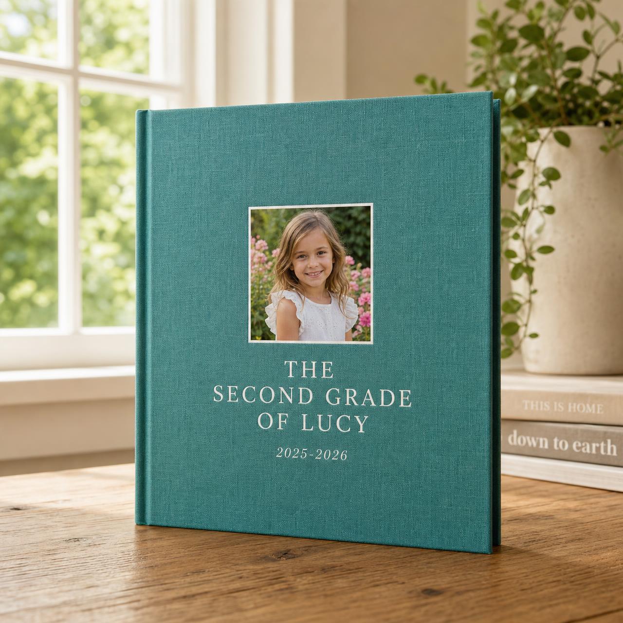 A hardcover keepsake book open to a page with school photos and a handwritten caption.
